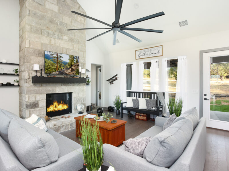 Living room with a stone fireplace and ceiling fan