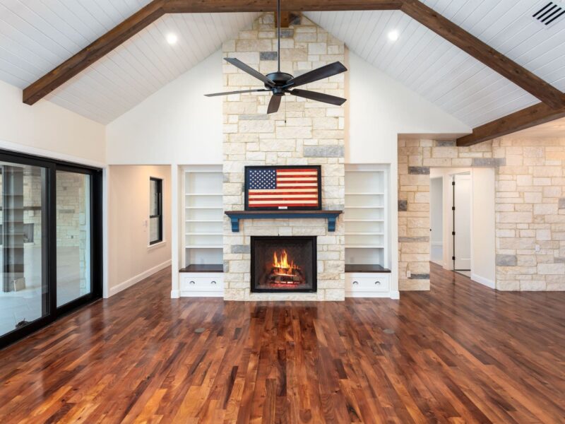Living room with a stone fireplace and exposed wood beams in The Riverwood