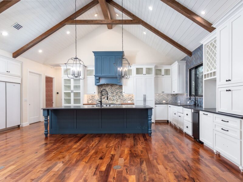 Kitchen with a blue island and vaulted wood beam ceiling