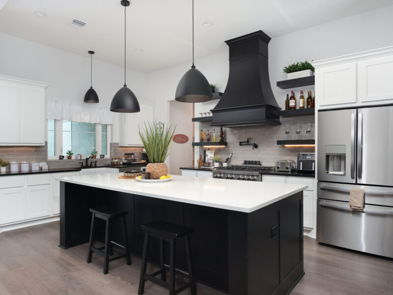 Kitchen with dark island, white cabinets and range hood