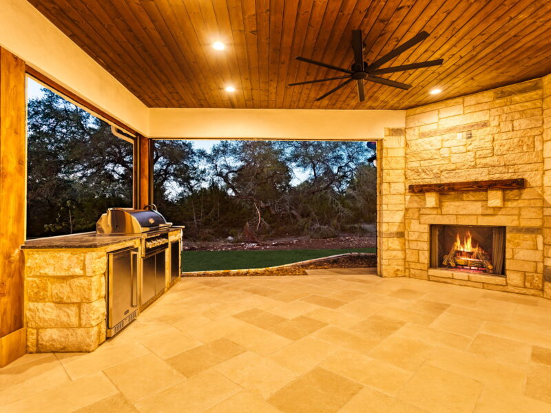 Covered outdoor patio with grill and stone fireplace