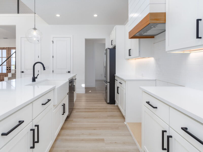 White kitchen island with wood range hood and pendant lighting