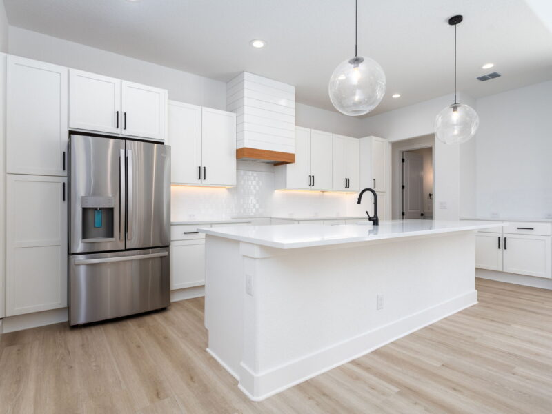 White kitchen with an island and stainless steel refrigerator